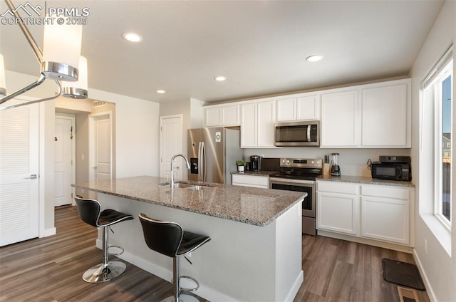 kitchen with light stone countertops, appliances with stainless steel finishes, sink, and white cabinets