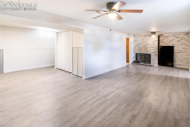 unfurnished living room featuring a brick fireplace, light hardwood / wood-style flooring, and ceiling fan