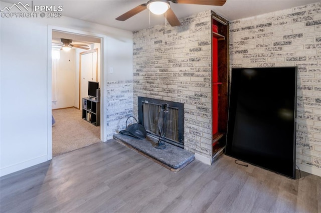 unfurnished living room with ceiling fan, hardwood / wood-style floors, and a brick fireplace