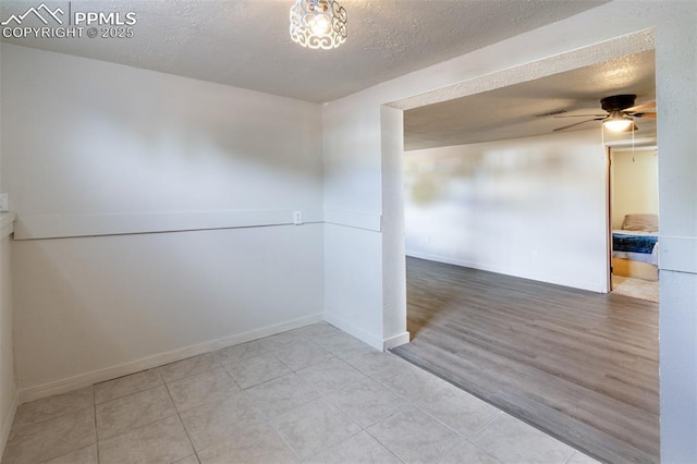 tiled empty room featuring ceiling fan and a textured ceiling