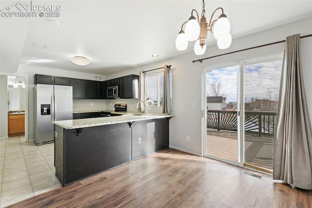 kitchen featuring sink, hanging light fixtures, appliances with stainless steel finishes, a kitchen breakfast bar, and kitchen peninsula