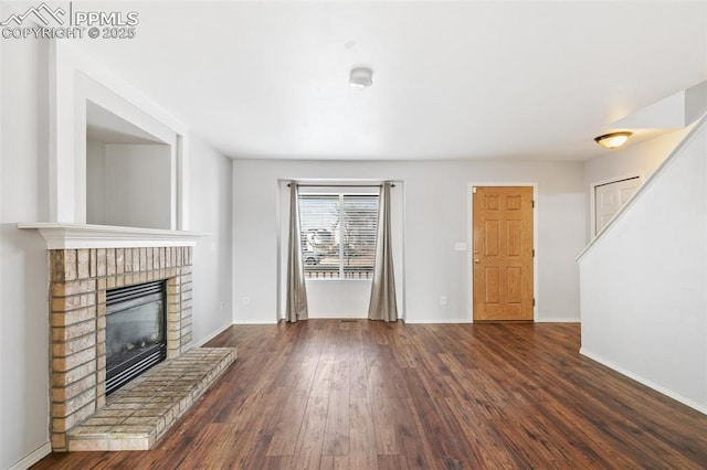 unfurnished living room featuring dark hardwood / wood-style floors and a brick fireplace