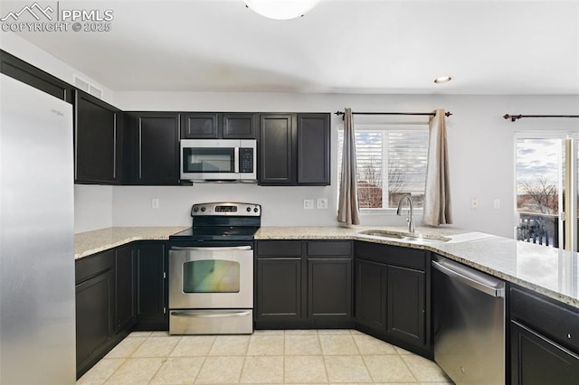 kitchen with light tile patterned flooring, appliances with stainless steel finishes, light stone countertops, and sink