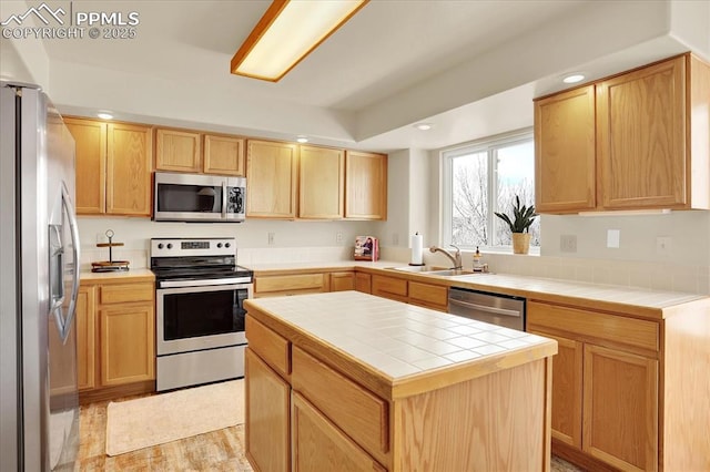 kitchen featuring stainless steel appliances, a kitchen island, sink, and tile countertops