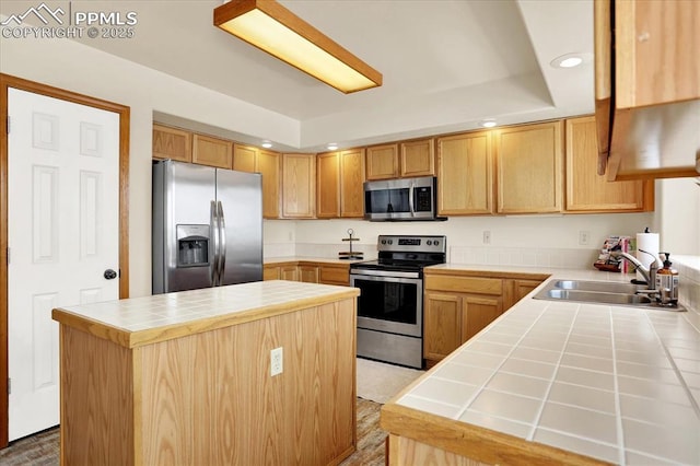 kitchen featuring sink, tile countertops, stainless steel appliances, and a kitchen island