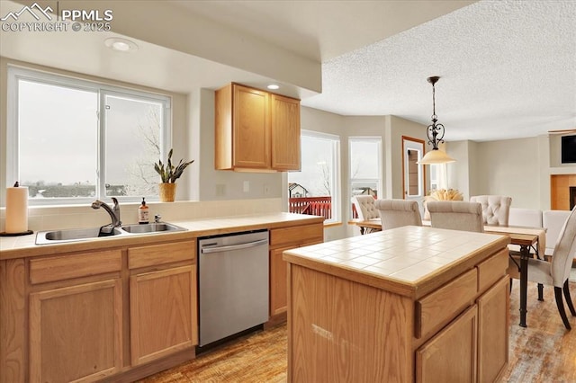 kitchen featuring tile countertops, dishwasher, sink, hanging light fixtures, and a center island