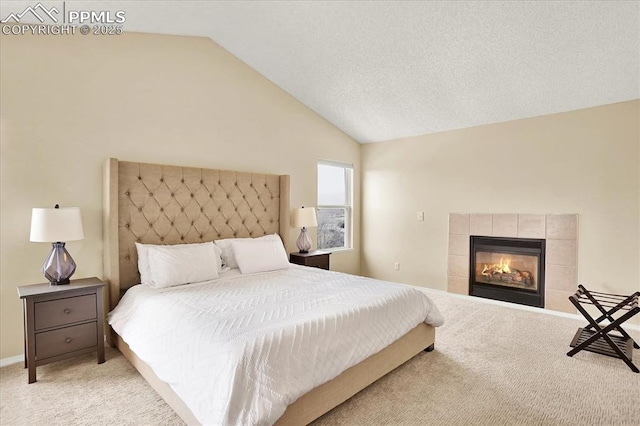 bedroom with a tile fireplace, lofted ceiling, light carpet, and a textured ceiling