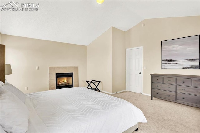 carpeted bedroom featuring lofted ceiling and a tiled fireplace