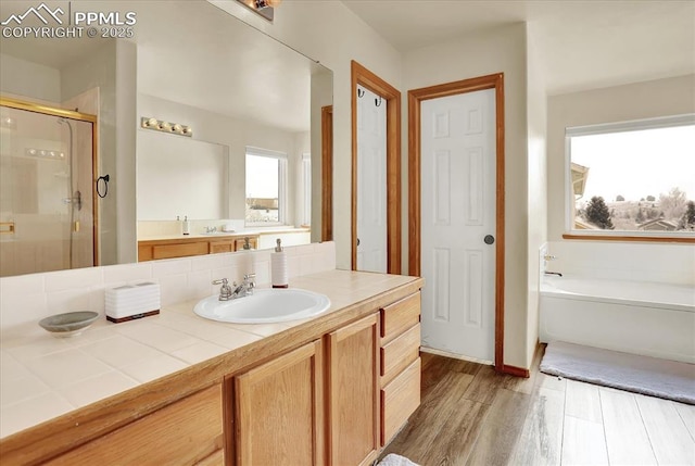 bathroom with vanity, hardwood / wood-style flooring, a healthy amount of sunlight, and separate shower and tub