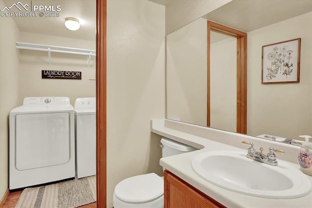 bathroom with vanity, hardwood / wood-style floors, independent washer and dryer, and toilet