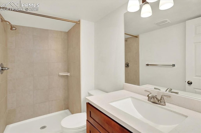 bathroom featuring vanity, toilet, and a tile shower