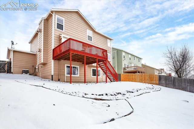 snow covered rear of property with a wooden deck