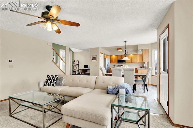 living room with ceiling fan, light carpet, and a textured ceiling