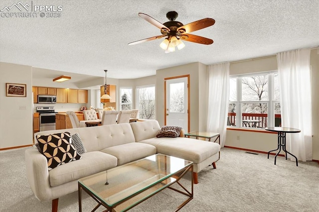 living room featuring ceiling fan, plenty of natural light, light carpet, and a textured ceiling