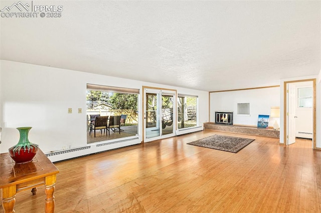 unfurnished living room featuring hardwood / wood-style floors, a textured ceiling, and a baseboard heating unit