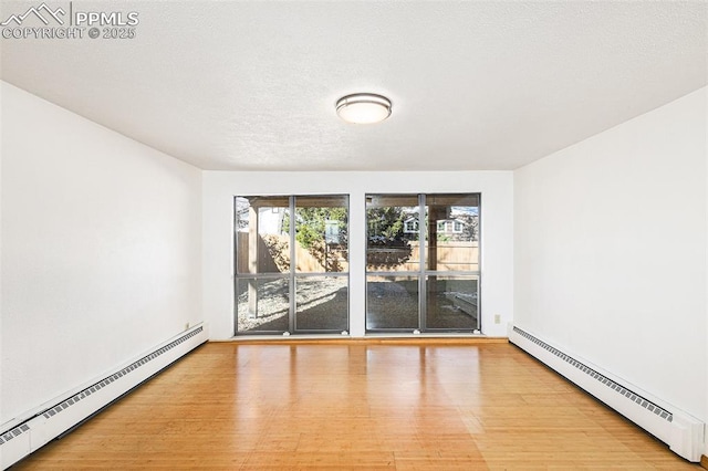 empty room with a baseboard heating unit, a textured ceiling, and light wood-type flooring