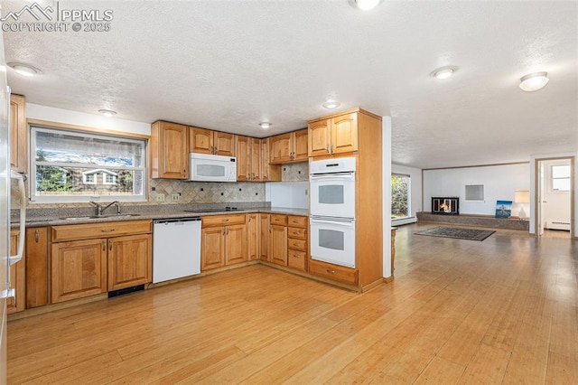 kitchen with a baseboard heating unit, a healthy amount of sunlight, sink, and white appliances