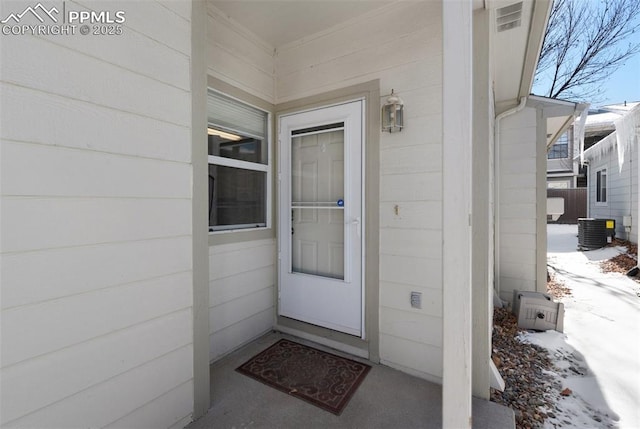 snow covered property entrance with central AC unit