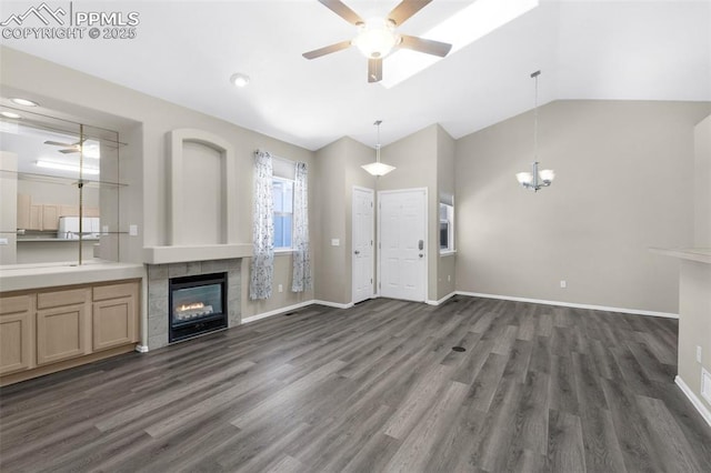 unfurnished living room with lofted ceiling, dark hardwood / wood-style floors, a tiled fireplace, and ceiling fan with notable chandelier