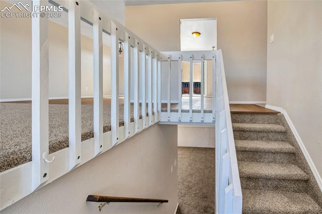 stairway featuring baseboards and carpet flooring