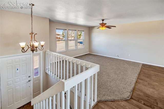 interior space with baseboards, wood finished floors, and ceiling fan with notable chandelier