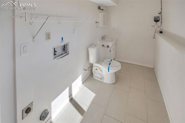 bathroom with tile patterned flooring, baseboards, a sink, and toilet