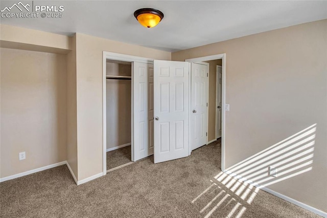 unfurnished bedroom with a closet, baseboards, and carpet flooring