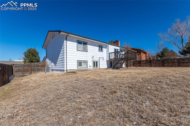 back of property featuring a fenced backyard, stairs, central AC unit, and a lawn