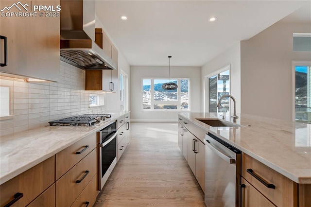 kitchen featuring sink, hanging light fixtures, stainless steel appliances, light stone counters, and extractor fan