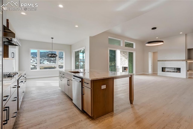 kitchen featuring sink, appliances with stainless steel finishes, white cabinets, a center island with sink, and decorative light fixtures