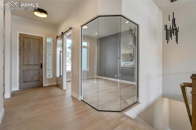 foyer entrance with light hardwood / wood-style floors and a barn door