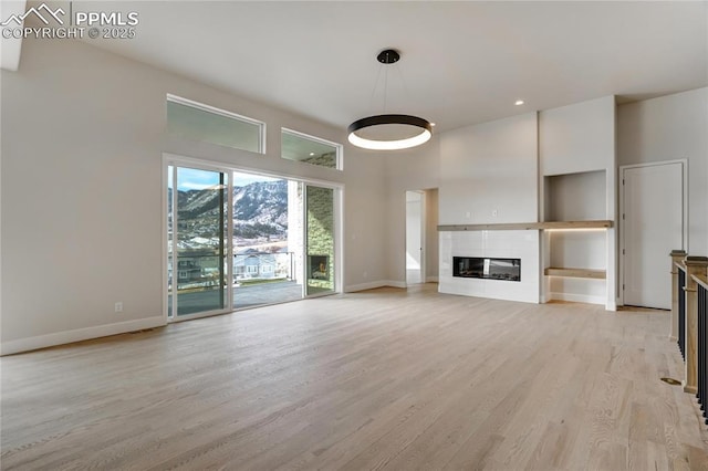 unfurnished living room with a towering ceiling and light hardwood / wood-style floors