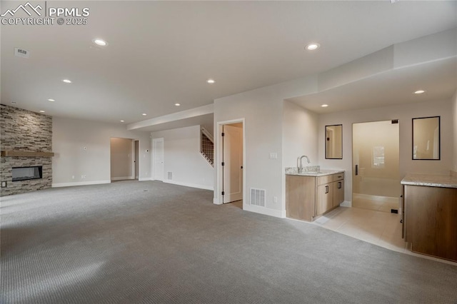 unfurnished living room with sink, light colored carpet, and a fireplace