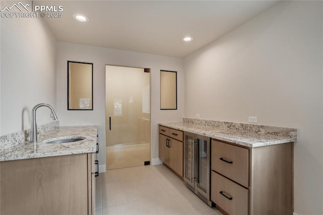 kitchen featuring light stone countertops, sink, light tile patterned floors, and beverage cooler