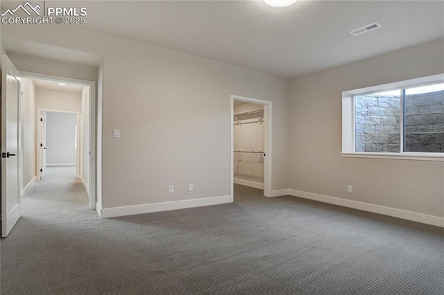 unfurnished bedroom featuring a walk in closet and carpet floors