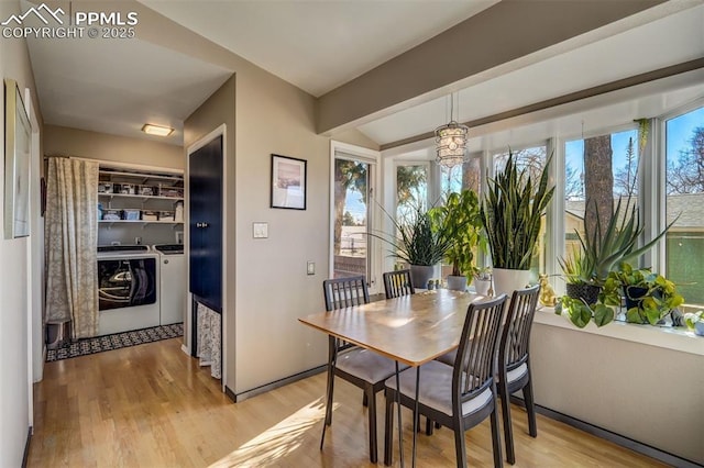 dining area with separate washer and dryer, light hardwood / wood-style floors, and vaulted ceiling with beams