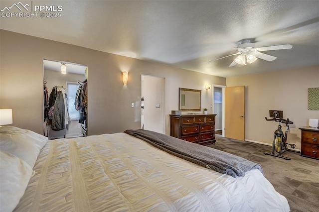 bedroom with a textured ceiling, a spacious closet, ceiling fan, and carpet flooring