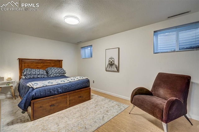 bedroom featuring light hardwood / wood-style floors and a textured ceiling