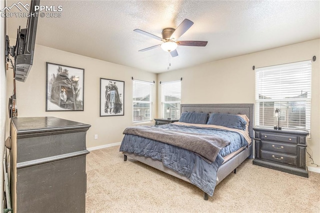 bedroom featuring ceiling fan, a textured ceiling, and light colored carpet