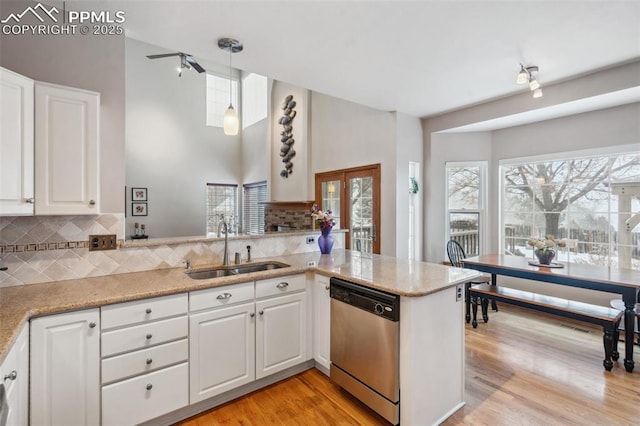 kitchen featuring sink, white cabinetry, hanging light fixtures, stainless steel dishwasher, and kitchen peninsula