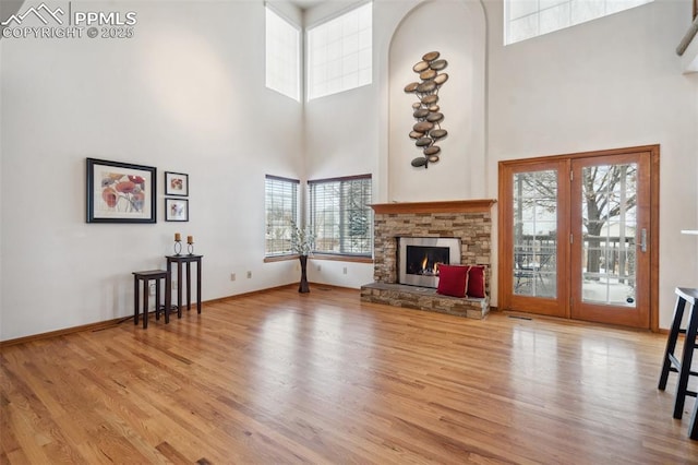 unfurnished living room with a towering ceiling, a fireplace, and light wood-type flooring