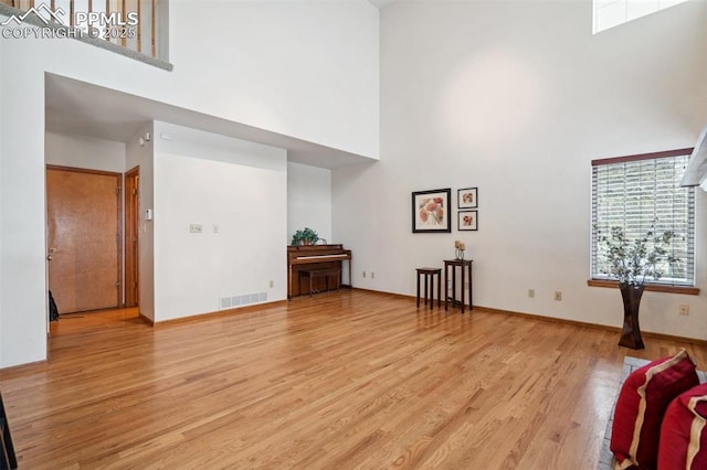 unfurnished living room with a towering ceiling and light hardwood / wood-style floors