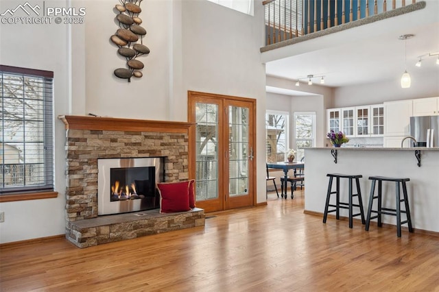 living room with a towering ceiling, a fireplace, and light hardwood / wood-style floors