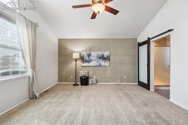 interior space with vaulted ceiling, a barn door, carpet, and ceiling fan