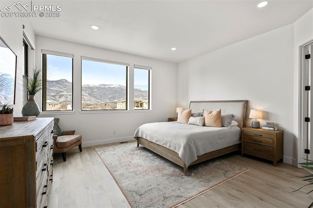 bedroom with a mountain view and light hardwood / wood-style floors