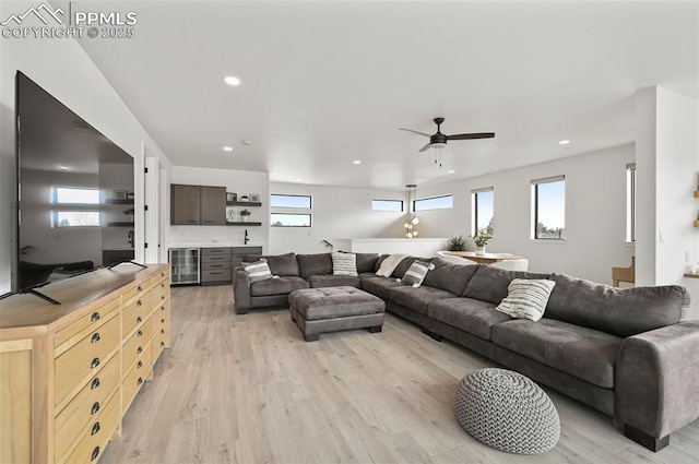 living room with wine cooler, a healthy amount of sunlight, and light wood-type flooring