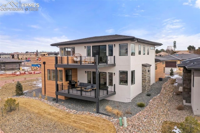 back of house with a balcony, an outdoor hangout area, and a lawn