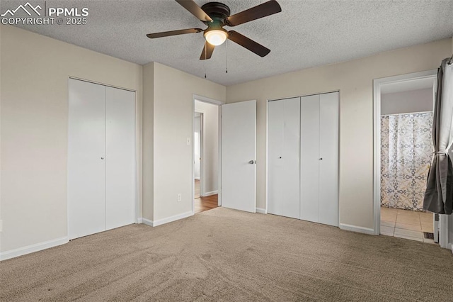 unfurnished bedroom featuring carpet floors, two closets, and a textured ceiling