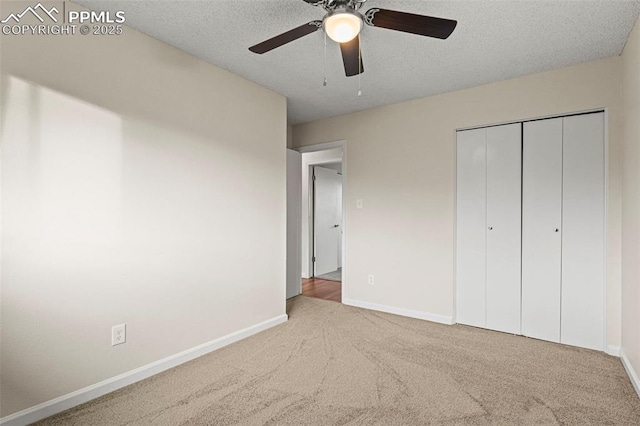 unfurnished bedroom with ceiling fan, light colored carpet, a closet, and a textured ceiling