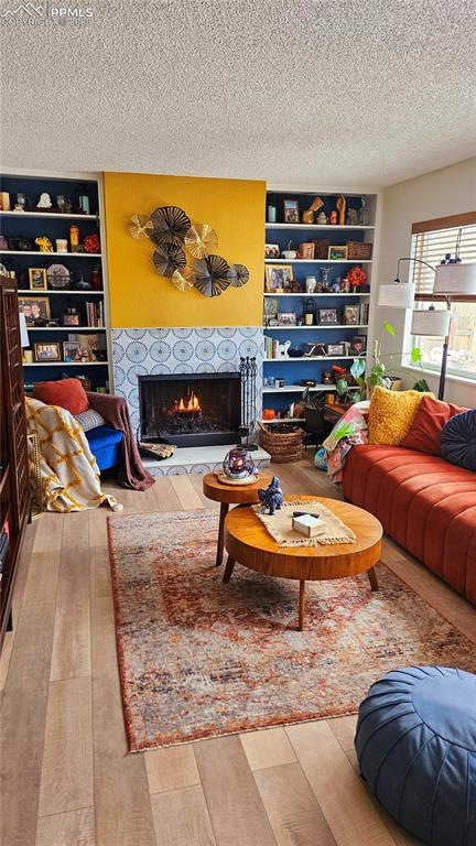 living room featuring a tiled fireplace, hardwood / wood-style flooring, and a textured ceiling